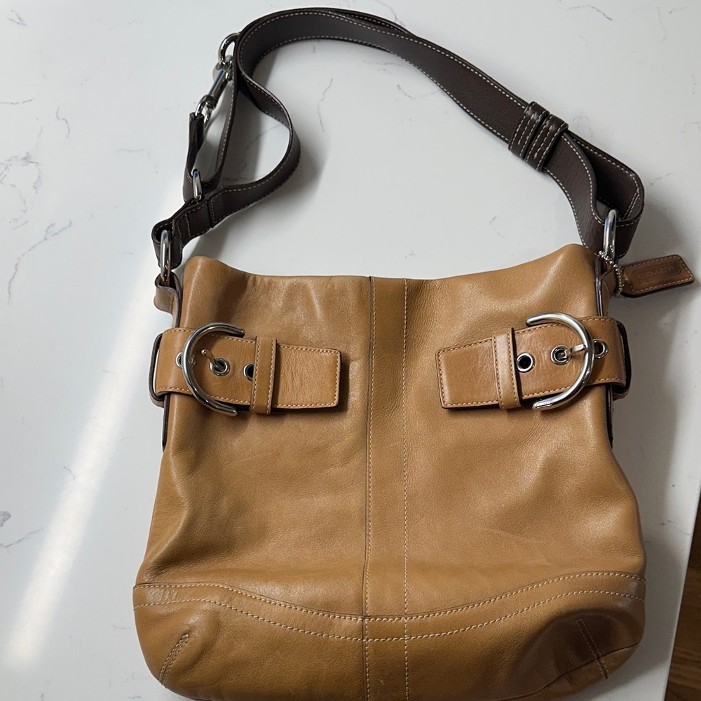 Vintage tan leather Coach shoulder bag with adjustable strap and buckle detail